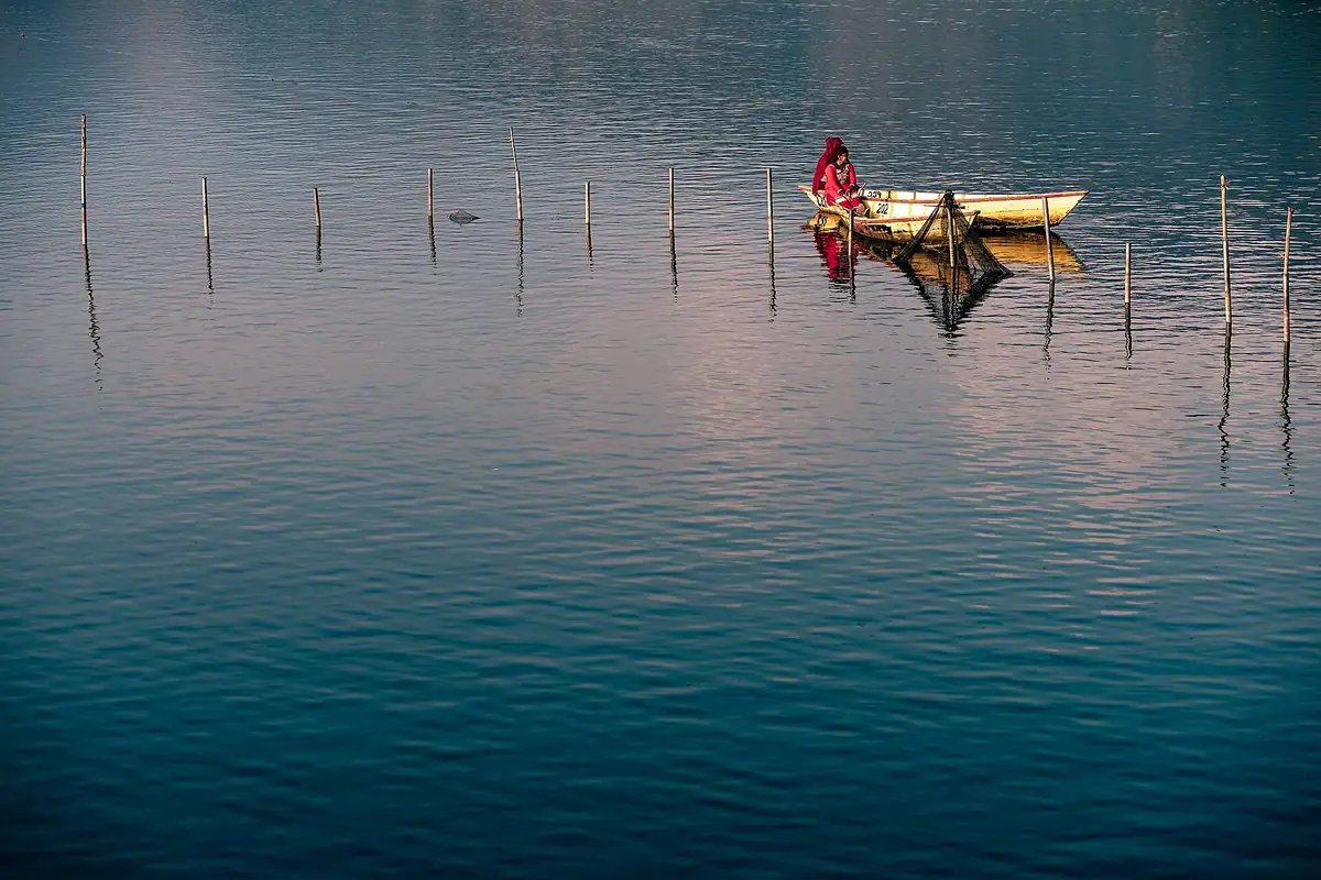A lone wooden boat on Phewa Lake at dusk