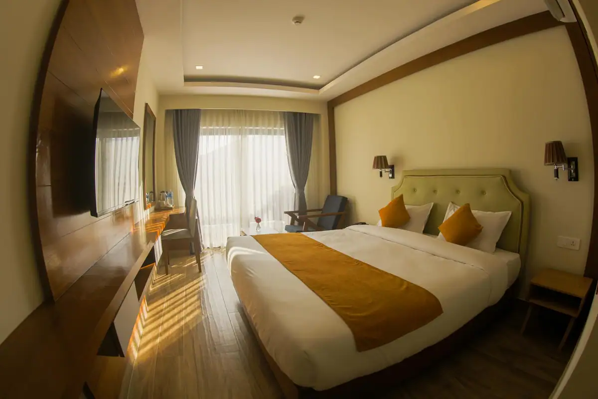 Deluxe king room with warm lighting, upholstered headboard and balcony doors